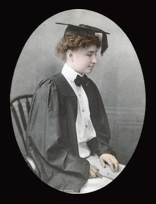 Helen Keller in her graduation gown, seated, facing right, colored.