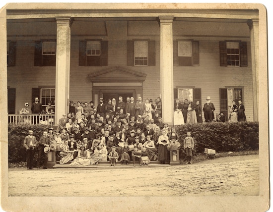 Group photograph of the first summer American Association To Promote Teaching Speech To The Deaf meeting taken on a Lake George porch with Alexander G. Bell positioned center with beard.