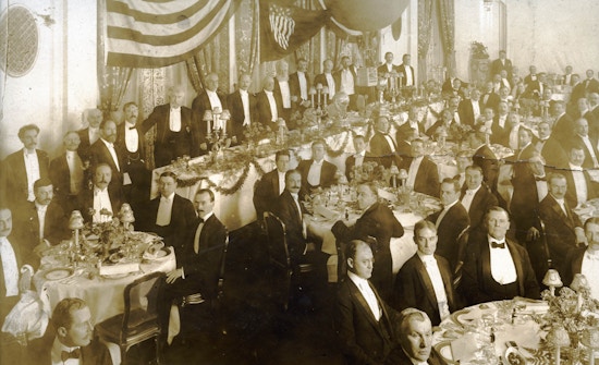 Group of formally dressed men at banquet.