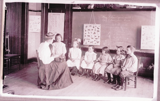 Six Horace-Mann students sit semi-circle around a teacher while one student stands left.
