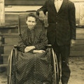 Elderly Man And Woman With Wheelchair,  Woman dressed in long dress.