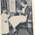A boy and a woman with eye chart.