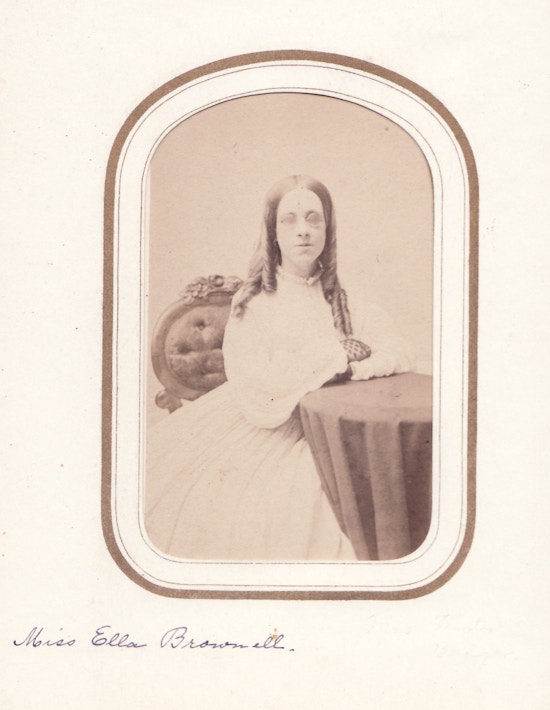Miss Ella Brownell, portrait, at table, facing camera, with glasses.