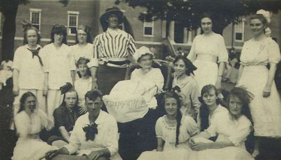Outdoor photograph of fifteen patients and staff dressed in costume, at the Rome State School for the Mentally Retarded.  A woman holds a sign that reads "champions."