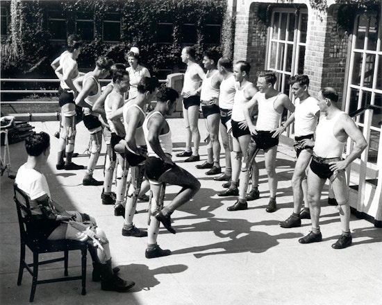 Two lines of men, most leg amputees, perform balancing exercises.