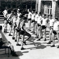 Two lines of men, most leg amputees, perform balancing exercises.