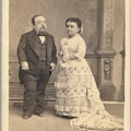 A short-statured man and woman dressed formally.
