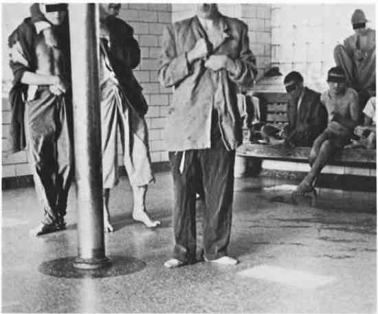 Partially dressed men standing on a tile floor.