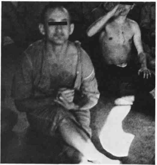 Two partially dressed men sitting on a floor,