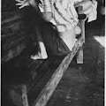 Woman crouching on a wooden bench.