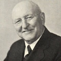 Portrait of Edar J. Helms, an elderly balding man with glasses.