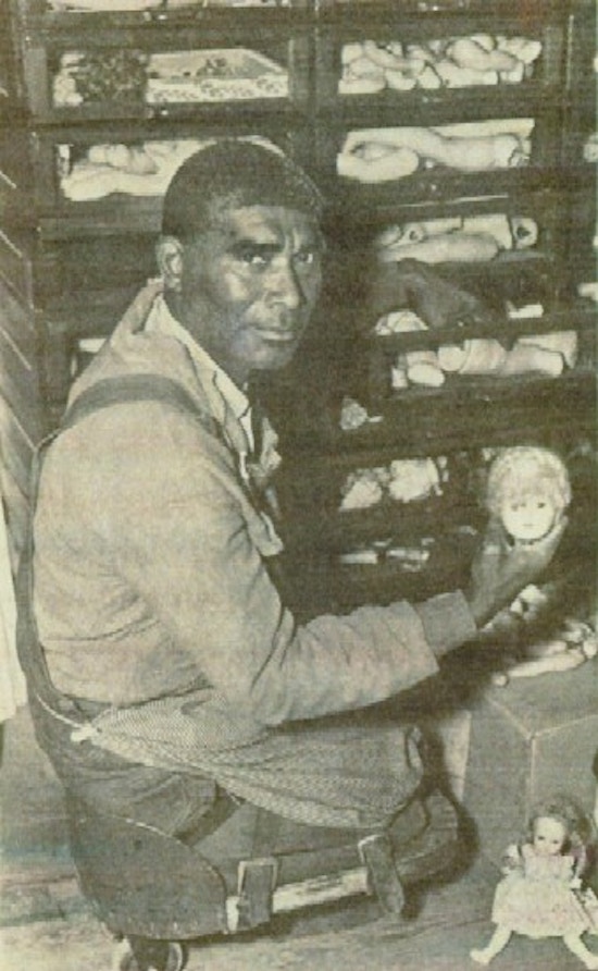 An African African man, a double amputee, works on a case of broken dolls.