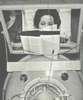 A woman in an iron lung reads a book using a mouthstick.