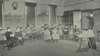 A group of boys and girls in a semi-circle engaged in sewing.