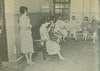 Seven women, most barefoot, sit on benches in a room.