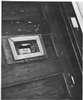 A man looks through the small window of a door.