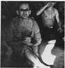 Two partially dressed men sitting on a floor,