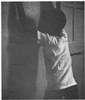 A young African-American man with his hands up on a wall.
