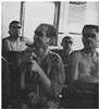 Four men, some partially dressed, sitting on benches.