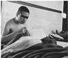 A naked man sitting up in a bed.