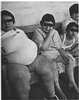 Women, one obese, sitting on a wooden bench.