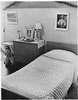A room with a bed, a bureau, images of Jesus, a crucifix, and a stuufed animal.