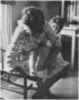 A woman putting a shoe on a child.