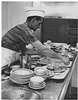 A man working at a sink with dirty dishes.
