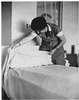 A woman making a bed.