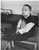 A boy sits holding a children's book, The Shy Little Kitten.