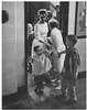 Women and children coming through a door.