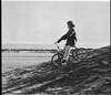A boy riding down a hill on a tricycle.