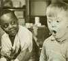 Two boys, One African American and the other white.  One smiles and the other appears to be singing.