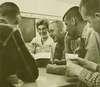 A woman showing a Dr. Seuss book to four teenage boys.