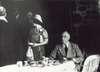 FDR sits at a table next a standing Queen Elizabeth.