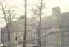 A stone house during construction, seen through trees.