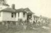 A group of men in front of a single-storied white building.
