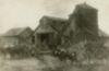 At a barn, young men unload cornstalks from wagons pulled by oxen.