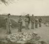 Seven young men and boys stand by a pile of rocks.