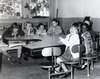 Seven children sit at a table.  Three of the children have Down Syndrome.