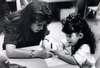 A teacher helps a young girl write her name.