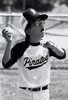 A with glasses wearing a baseball uniform prepares to throw a baseball.