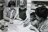 Two adults showing two children how to color.
