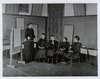 Four young deaf girls sit in a classroom practicing speech lessons with their teacher