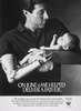 A man with a prosthetic right arm cradles a baby.