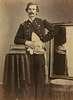 Henry Barnum in uniform.  His coat and shirt are pulled aside from his left hip revealing a wound through which a string passes.