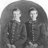 Photograph of two young boys with buttoned coats and bow ties.