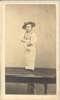 A short-statured man stands on a table.
