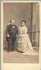 A short-statured man and woman dressed formally.