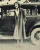 A woman stands next to a car.